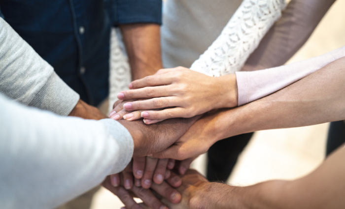 Divers group of people with hands together on top of one another. 